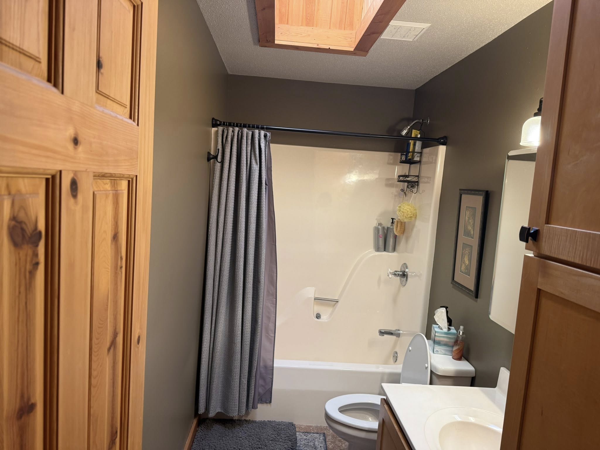 Bathroom with freshly painted sage-green walls and stained pine cabinets